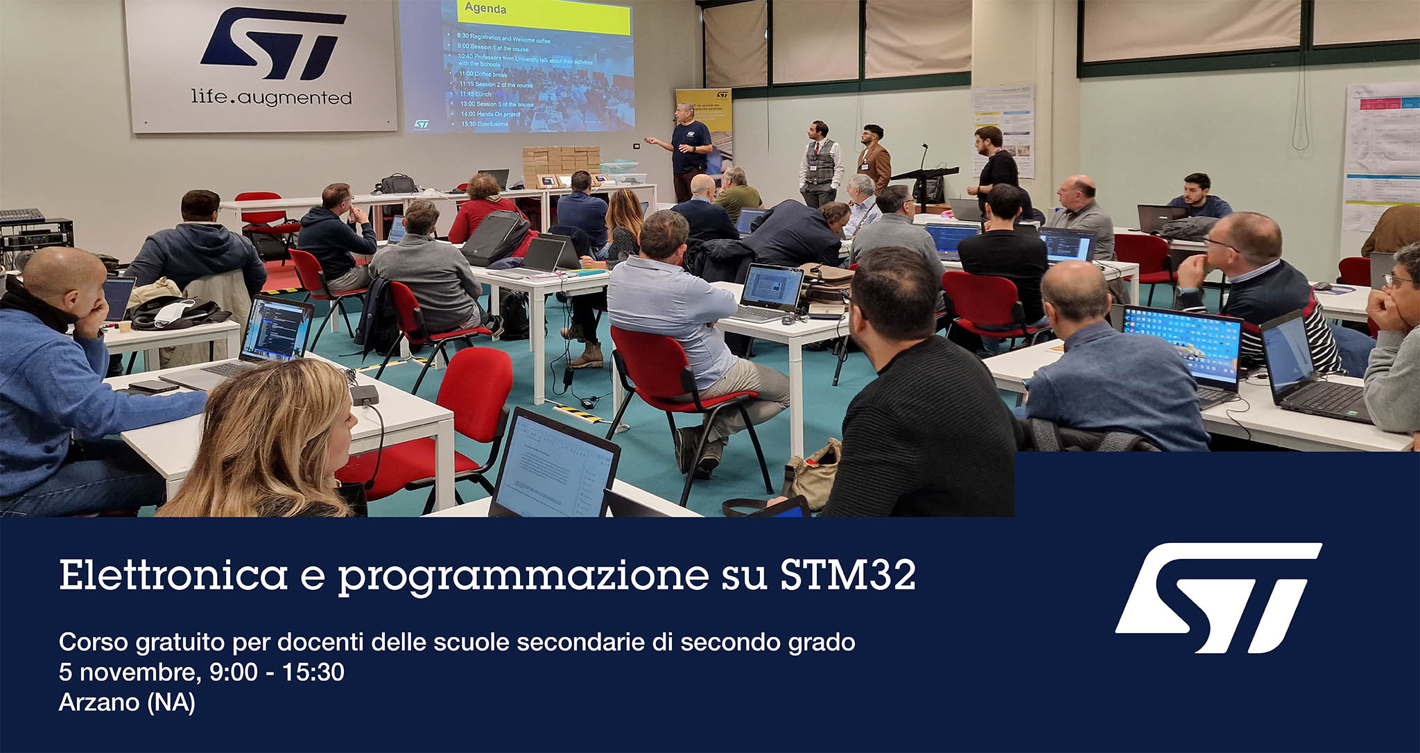 Gruppo di persone in sedute davanti ai loro computers in auditorium durante il corso